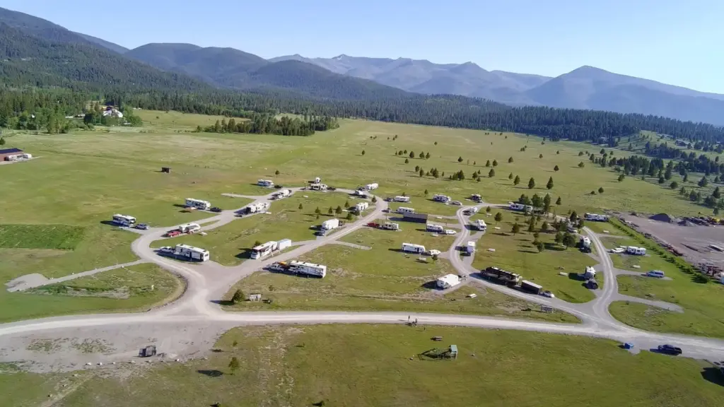 Aerial view of Lost Moose Meadows RV Campground with RVs on the loops and mountains behind it, Lincoln, Montana