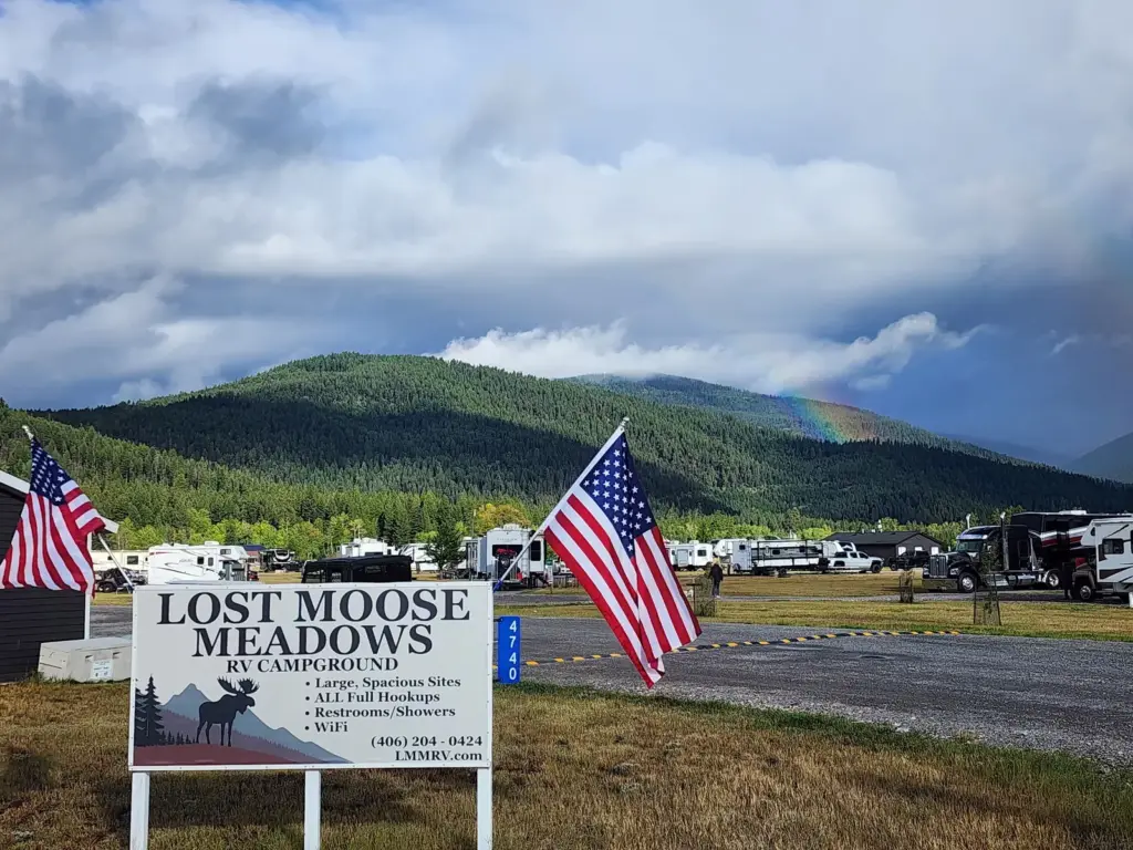 The Lost Moose Meadows sign and 4740 address marker at our entrance on Highway 200, with a rainbow over the mountains