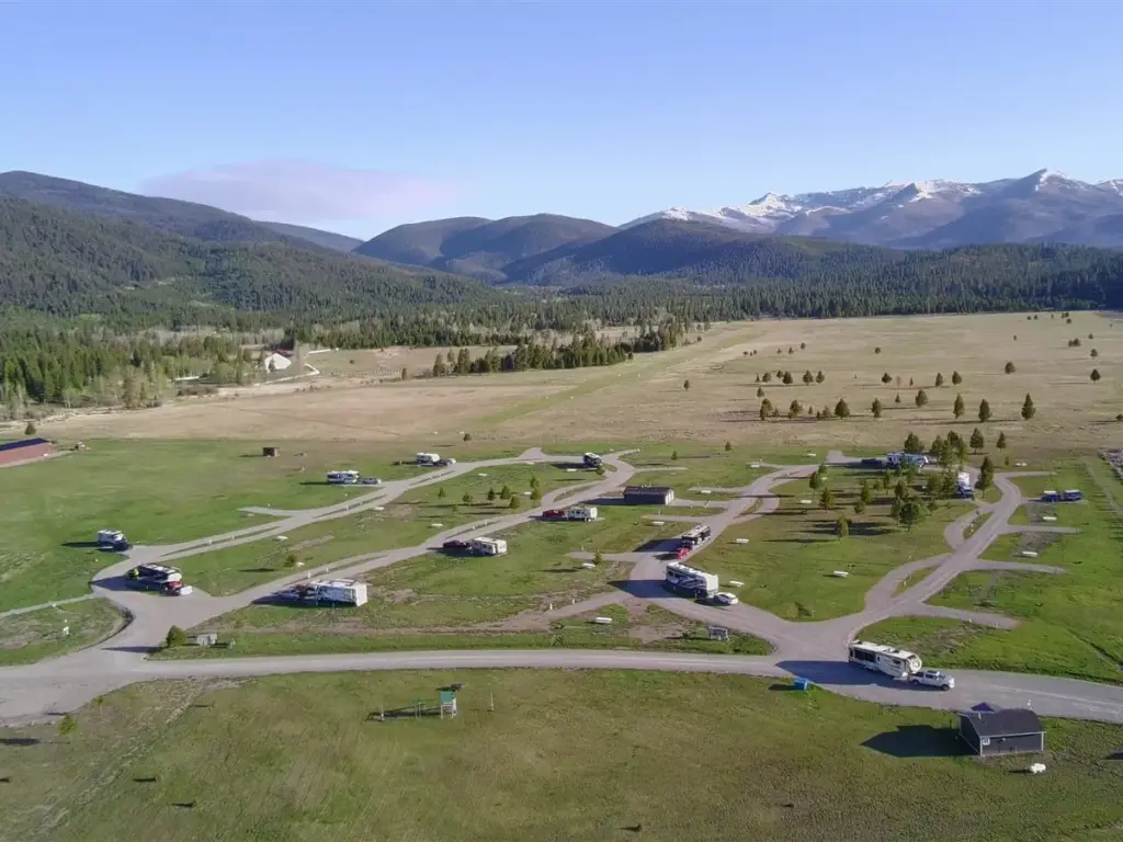 Aerial view of the finished campground loops and RV sites in green grass below snow capped mountains